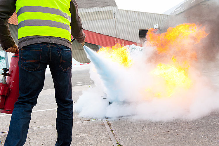 Brandschutzhelfer bei einer praktischen Löschübung Eine Person löscht bei einer Brandschutzübung mit einem Feuerlöscher einen Entstehungsbrand.
