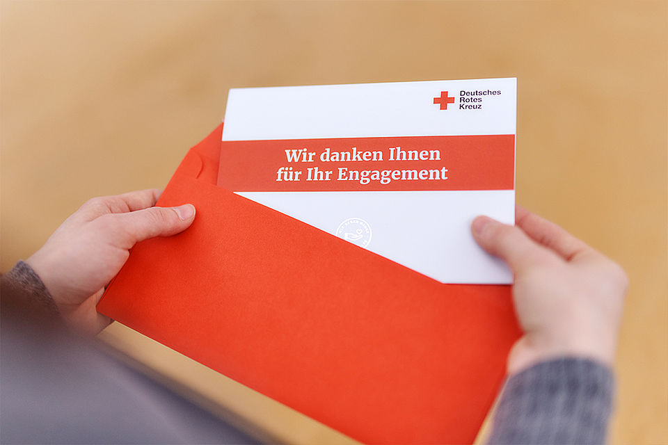 Jemand öffnet einen Briefumschlag mit einem Dankesbrief